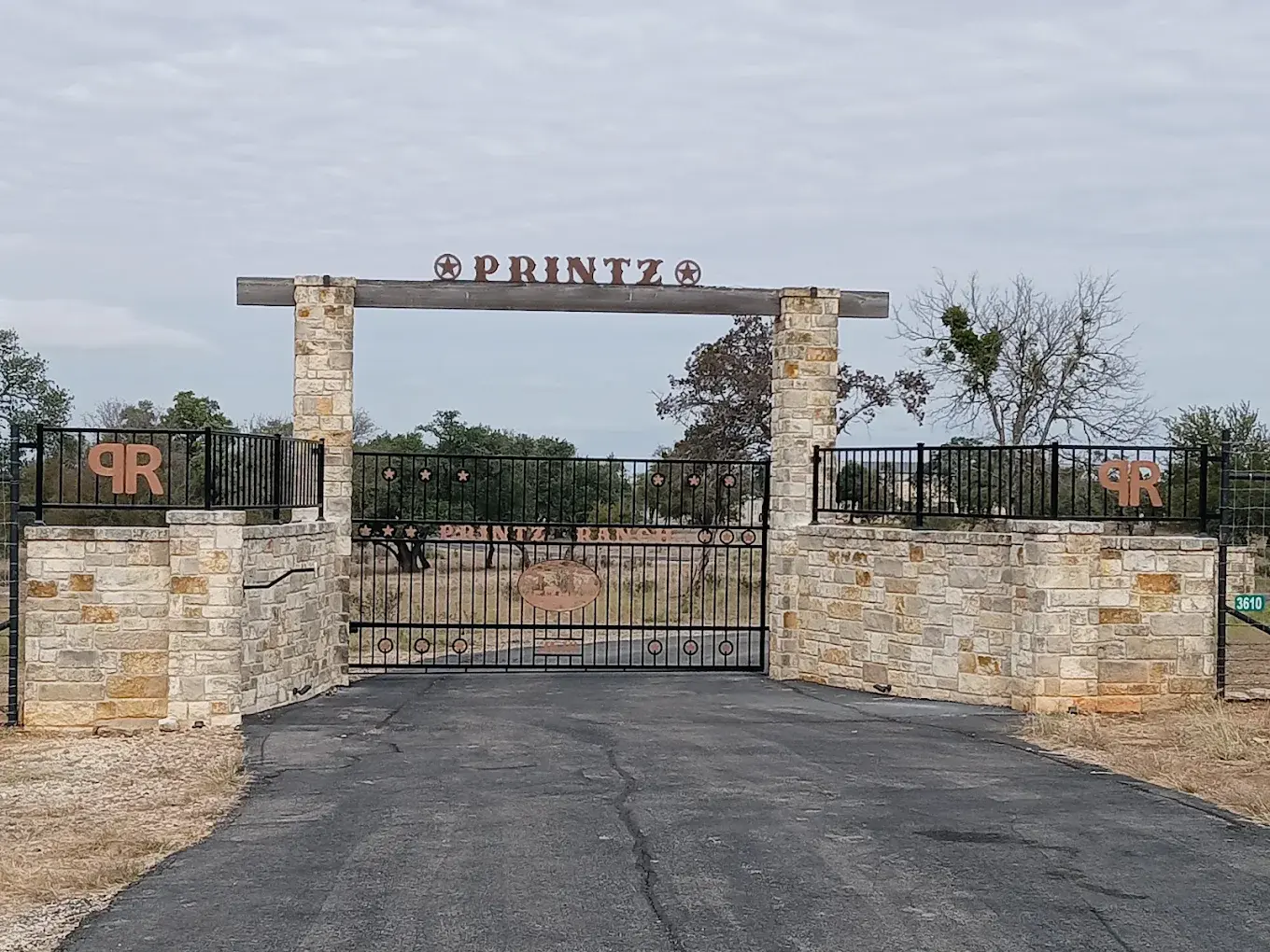 Custom welded steel ranch entrance gate at the front of a Texas Hill Country property